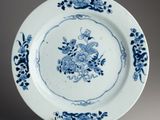 blue and white plate with flowers on it on a stand