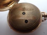 a gold pocket watch sitting on a white surface