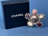 a close up of a box of chanel brooches on a blue surface