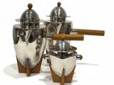three silver pots and a wooden spoon on a white surface