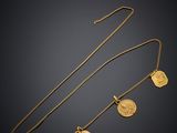 a gold necklace with a heart and two charms on it