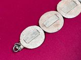 a close up of a silver bracelet on a pink surface