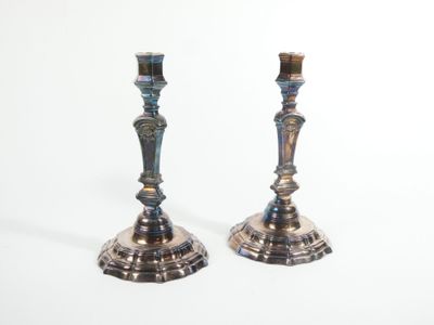 pair of silver candlesticks on a white surface with a white background