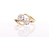 a yellow gold ring with two diamonds on a white background