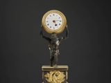 une statue d'un homme tenant une horloge au-dessus d'une table
