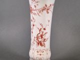 a white vase with a red floral design on it