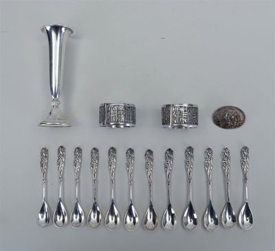 plusieurs cuillères en argent, une coupe en argent et un centime posés sur une table
