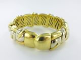 a close up of a gold and silver bracelet on a white surface