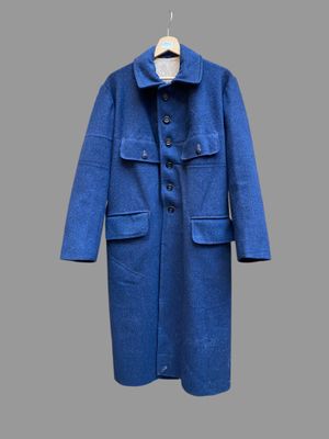 Le manteau est bleu et comporte des boutons au niveau du col.