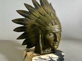 statue représentant la tête d'un Amérindien ornée de plumes, posée sur un socle en marbre