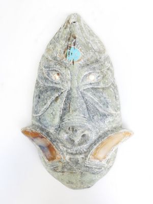 a stone mask hanging on a wall on a white background