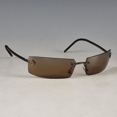 lunettes de soleil marron avec une monture noire et des verres marron sur un fond blanc