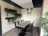 a dining room with a table and chairs and a potted plant on the wall
