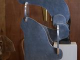 une sculpture en métal posée sur une table en bois, avec un chien en arrière-plan