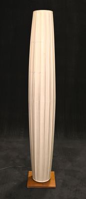 un grand vase blanc posé sur un socle en bois, sur fond noir