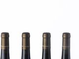 three bottles of wine are lined up in a row on a white surface