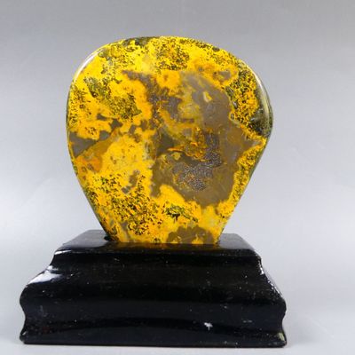yellow and black heart shaped stone on black base on white background
