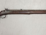 Un vieux fusil est accroché au mur d'une pièce.