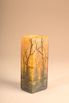 candle with a painting of trees on it sitting on a table