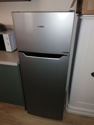 a silver refrigerator in a kitchen with a microwave on top of it