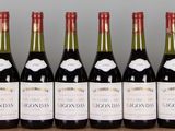 six bottles of wine are lined up on a wooden table
