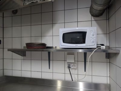 un micro-ondes posé sur une étagère métallique dans une cuisine