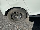 une petite voiture blanche avec un pneu à plat sur la route