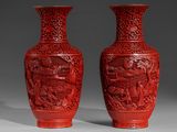 une paire de vases rouges ornés de motifs sculptés sur un fond gris