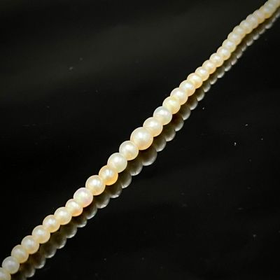un gros plan sur un fil de perles blanches sur une surface noire