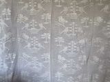 a white crocheted curtain with a bird design on it