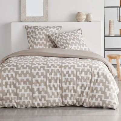 un lit blanc avec une couette beige et des oreillers dans une chambre
