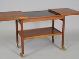 a small wooden table with a glass top on wheels