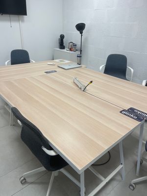 une table en bois entourée de chaises, avec une télévision accrochée au mur