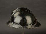 a silver helmet on a stand against a black background
