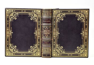 an old book with gold trim and a black cover on a white background