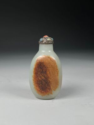 une petite bouteille en verre ornée d'un motif marron et blanc