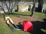 a red umbrella sitting on the ground next to a wooden bench