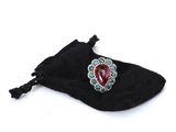 an image of a red heart shaped broocher sitting on top of a black bag