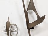 two metal sculptures that are sitting on a white surface
