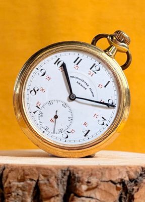 a gold pocket watch sitting on top of a piece of wood