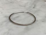 a close up of a silver bracelet on a marble surface