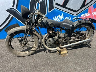 une vieille moto garée devant un mur recouvert de graffitis