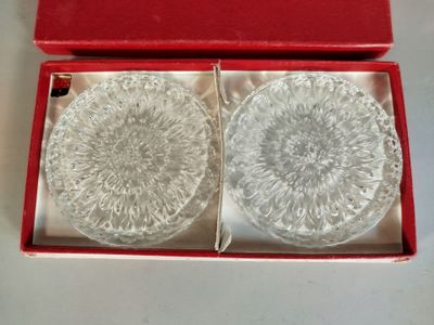 deux dessous de verre en verre dans une boîte rouge posée sur une table