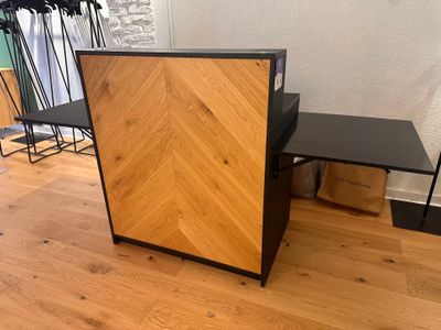 une armoire en bois avec un plateau noir, posée sur un parquet