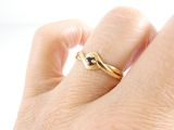 a woman ' s hand holding a gold ring with a black diamond