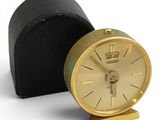 a small gold clock sitting on a black case