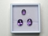 trois améthystes violettes dans une boîte blanche posée sur une table