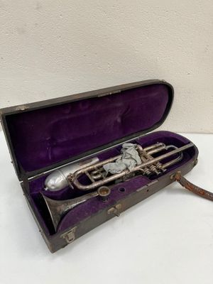 une vieille trompette dans un étui violet posée sur une surface blanche