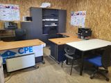 a room with a desk, chair, printer, and cabinets