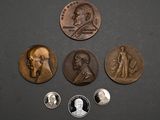 On voit plusieurs pièces de monnaie posées sur une surface noire, dont l'une porte le portrait d'un homme.